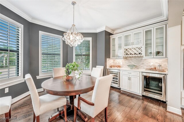 dining space featuring a chandelier, dark hardwood / wood-style flooring, beverage cooler, and crown molding