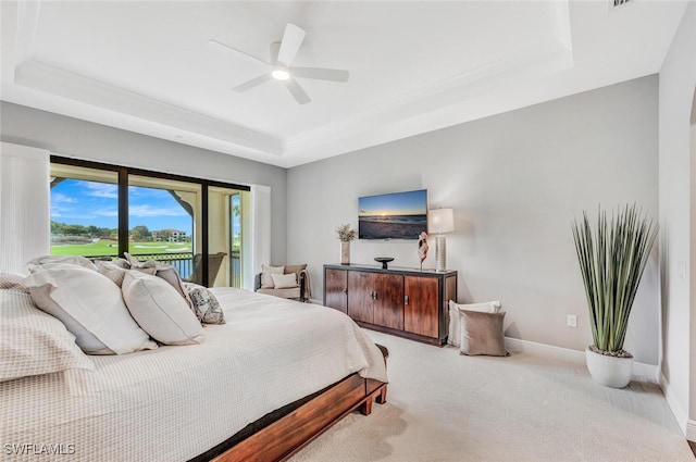 carpeted bedroom featuring ceiling fan, access to exterior, and a tray ceiling