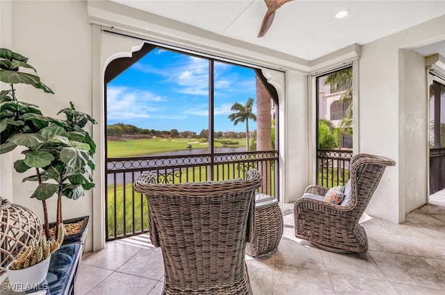 sunroom featuring a water view and ceiling fan