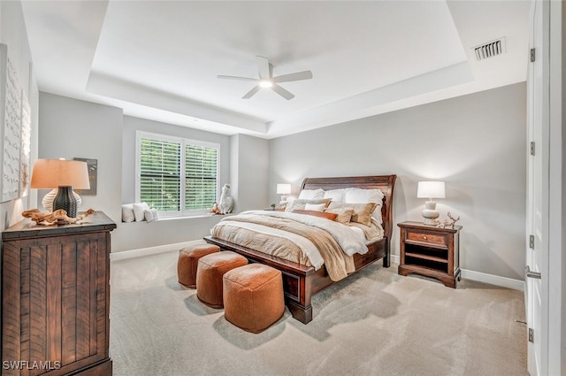 carpeted bedroom with a raised ceiling and ceiling fan