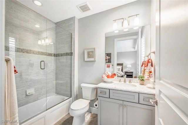 bathroom with visible vents, toilet, enclosed tub / shower combo, connected bathroom, and vanity