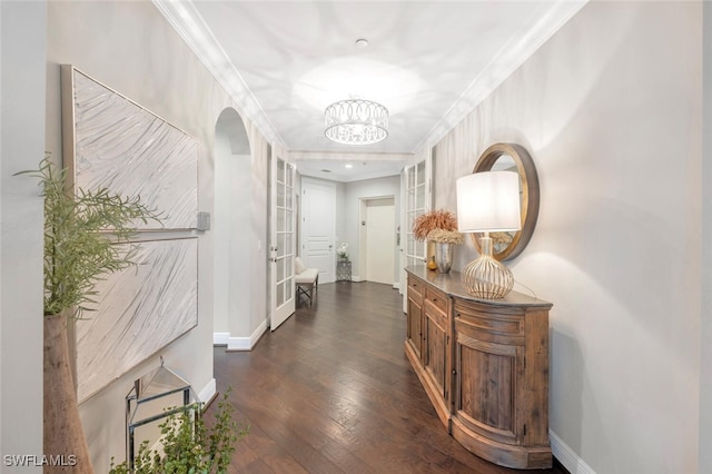 corridor featuring crown molding, baseboards, a notable chandelier, and dark wood finished floors