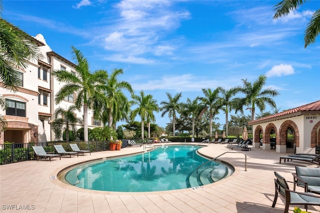 community pool with a patio and fence