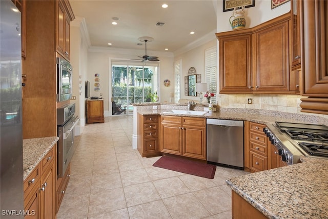 kitchen with sink, appliances with stainless steel finishes, light stone countertops, ceiling fan, and kitchen peninsula