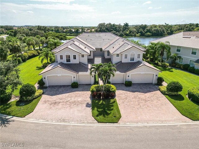 view of front of house featuring a water view, a garage, and a front lawn