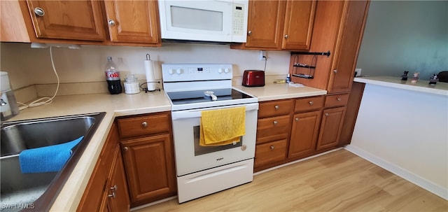 kitchen featuring sink, white appliances, and light hardwood / wood-style floors