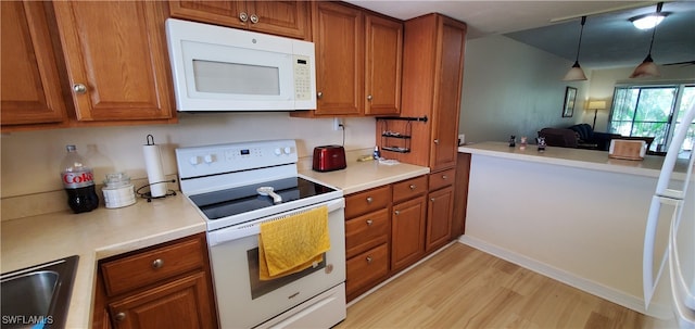 kitchen featuring light hardwood / wood-style floors, sink, pendant lighting, and white appliances