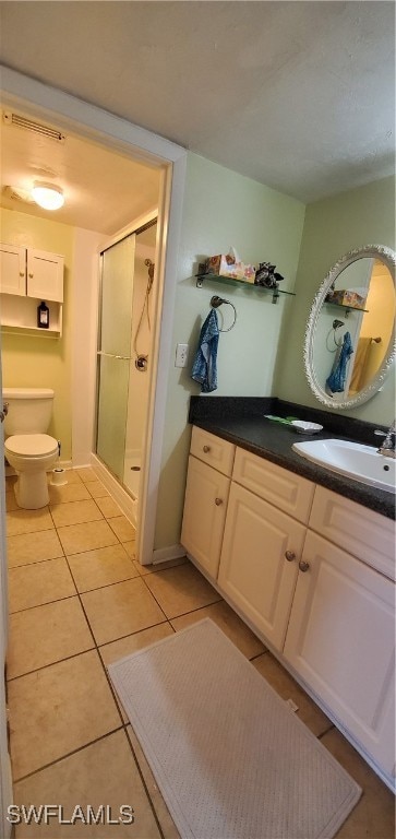 bathroom featuring tile patterned flooring, toilet, vanity, and walk in shower