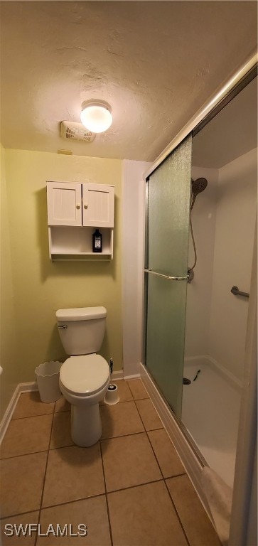 bathroom with tile patterned floors, a shower with shower door, and toilet