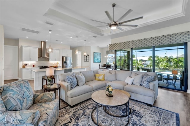 living area featuring ceiling fan, a raised ceiling, light wood-style flooring, and recessed lighting