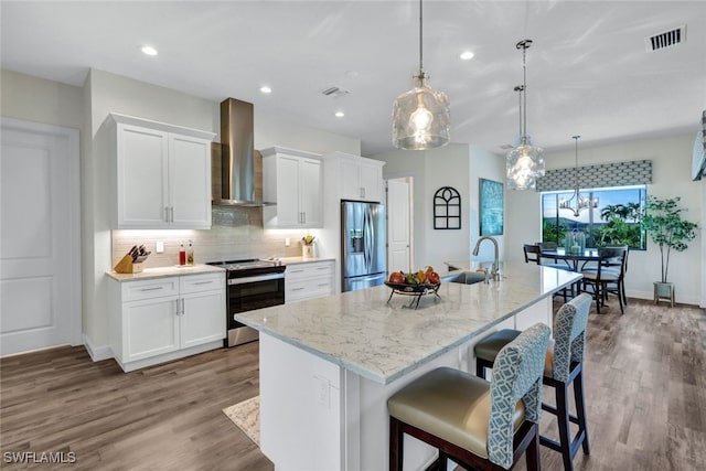 kitchen featuring wall chimney exhaust hood, appliances with stainless steel finishes, a sink, and white cabinets