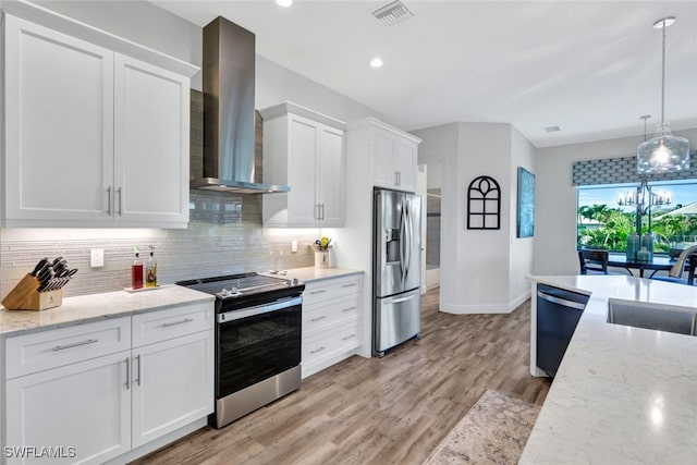 kitchen featuring visible vents, appliances with stainless steel finishes, white cabinetry, a sink, and wall chimney range hood