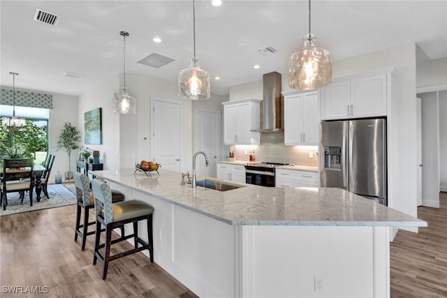 kitchen with tasteful backsplash, visible vents, appliances with stainless steel finishes, a sink, and wall chimney exhaust hood