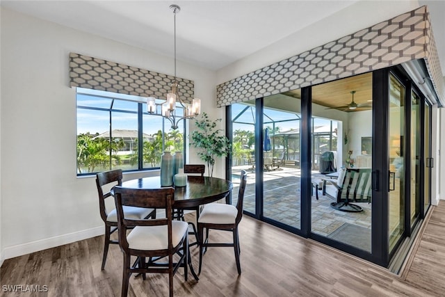 dining room with ceiling fan with notable chandelier, baseboards, and wood finished floors