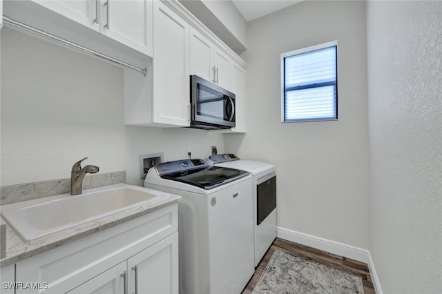 laundry area featuring separate washer and dryer, wood finished floors, a sink, baseboards, and cabinet space