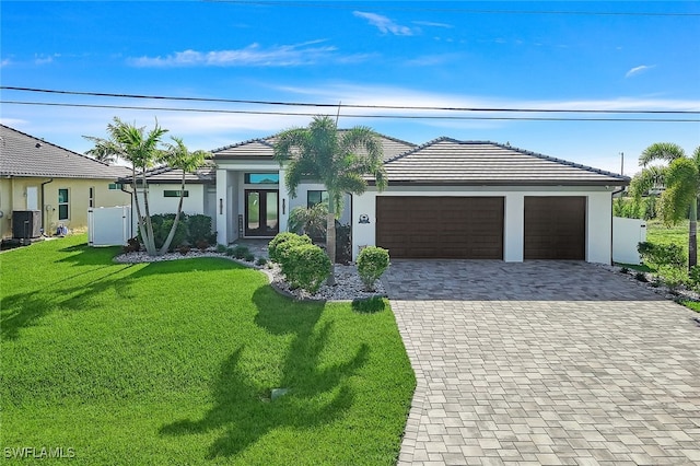 view of front of home with a garage, a front yard, and central air condition unit