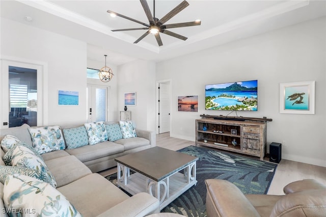 living room featuring ceiling fan with notable chandelier, hardwood / wood-style floors, and a tray ceiling