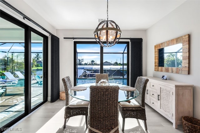 dining space featuring a wealth of natural light, light hardwood / wood-style flooring, and an inviting chandelier