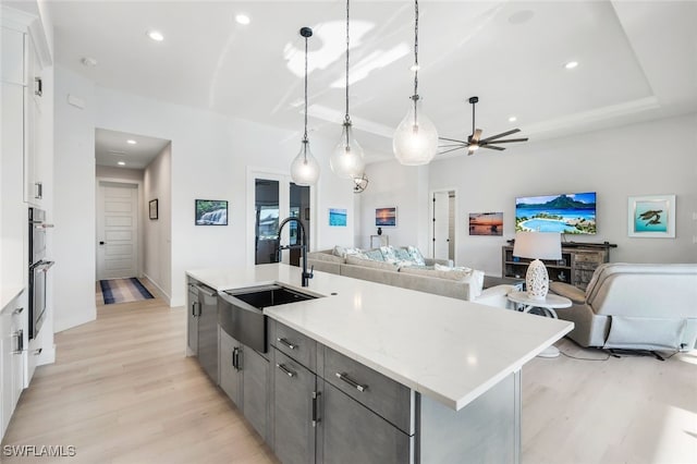 kitchen with white cabinets, sink, ceiling fan, and a center island with sink