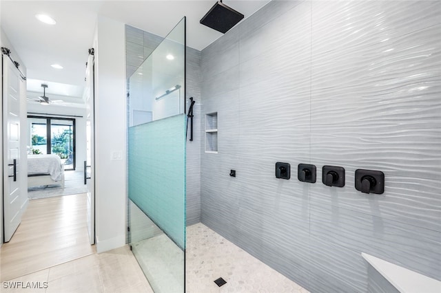 bathroom with tile patterned flooring, tile walls, ceiling fan, and a tile shower