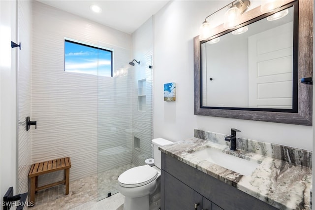 bathroom with vanity, toilet, and tiled shower