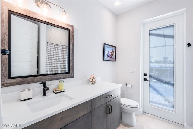 bathroom featuring plenty of natural light, vanity, toilet, and tile patterned flooring