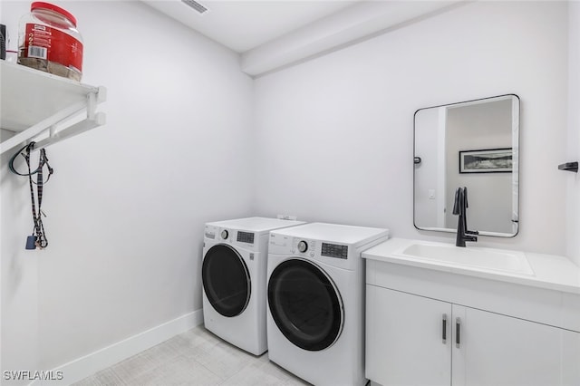 laundry room featuring washing machine and clothes dryer, cabinets, and sink