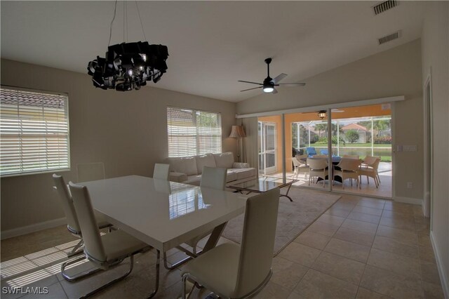 tiled dining space with lofted ceiling, ceiling fan with notable chandelier, visible vents, and baseboards