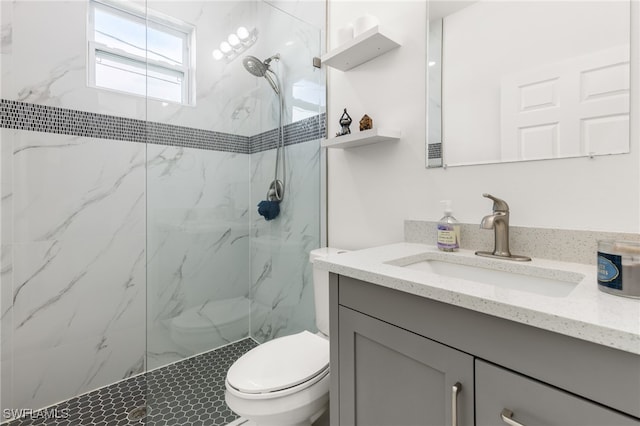 bathroom featuring a tile shower, vanity, and toilet