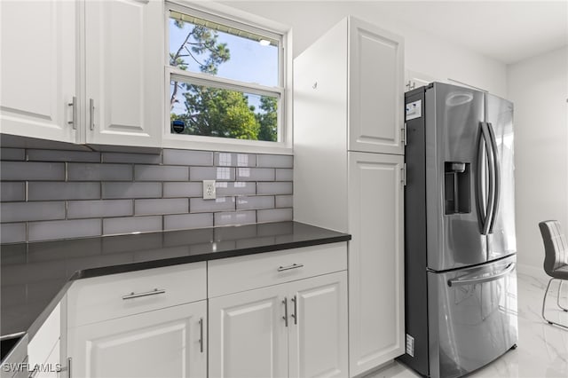 kitchen featuring white cabinets, stainless steel fridge, and backsplash