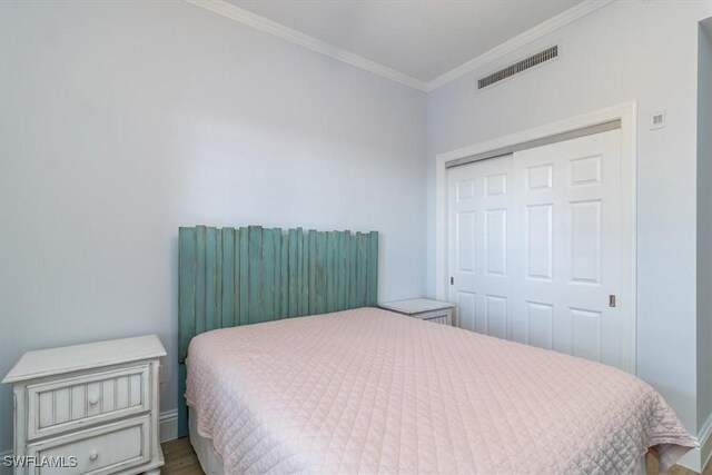 bedroom with crown molding, a closet, and wood-type flooring