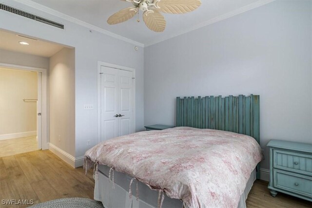 bedroom featuring hardwood / wood-style floors, crown molding, ceiling fan, and a closet