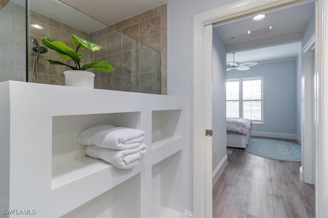 bathroom with tiled shower, wood-type flooring, and ceiling fan