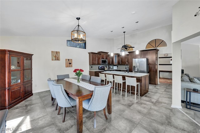 tiled dining room featuring sink, high vaulted ceiling, and ceiling fan with notable chandelier