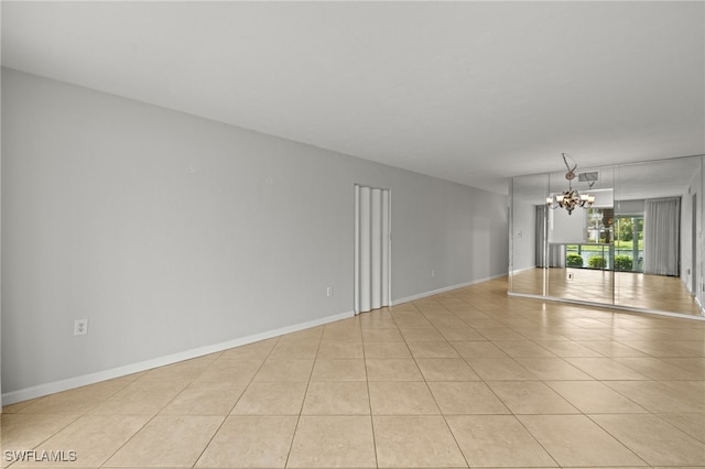 spare room featuring baseboards, visible vents, a chandelier, and light tile patterned flooring