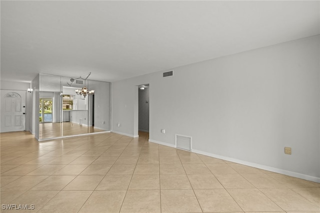 empty room with light tile patterned floors, baseboards, visible vents, and a chandelier