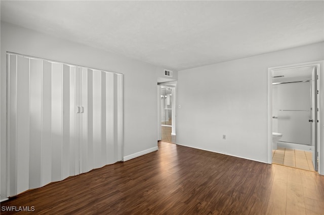 unfurnished bedroom with visible vents, dark wood-type flooring, and ensuite bathroom