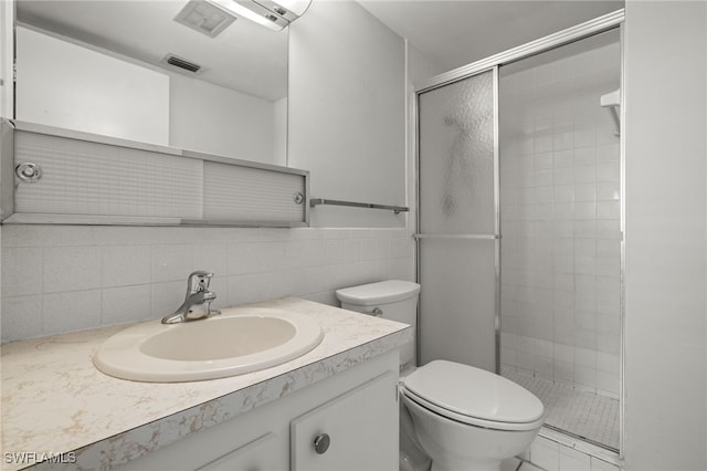 bathroom featuring visible vents, decorative backsplash, toilet, a stall shower, and vanity