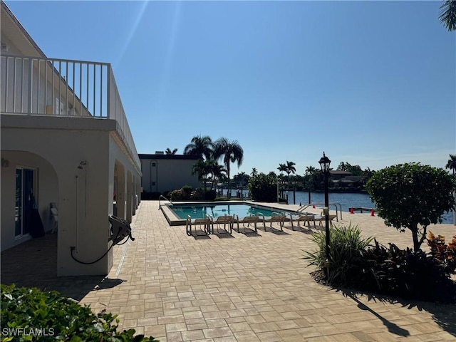 pool with a patio area and a water view