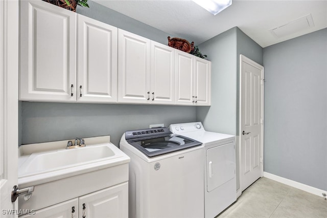 clothes washing area with cabinet space, baseboards, washer and dryer, a sink, and light tile patterned flooring