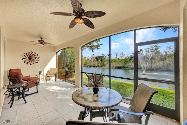 sunroom featuring a water view, a healthy amount of sunlight, and a ceiling fan