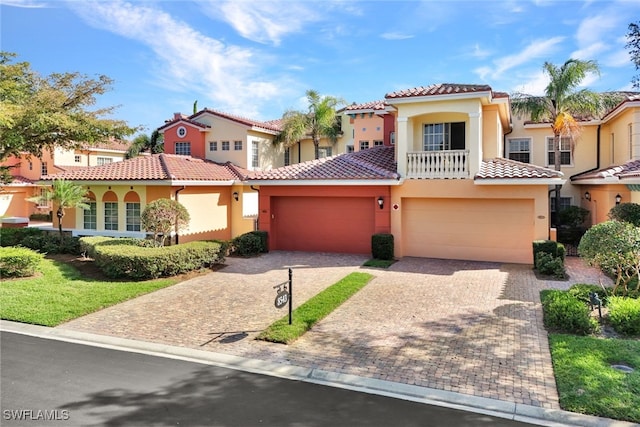 mediterranean / spanish house with decorative driveway, a tile roof, stucco siding, a garage, and a residential view