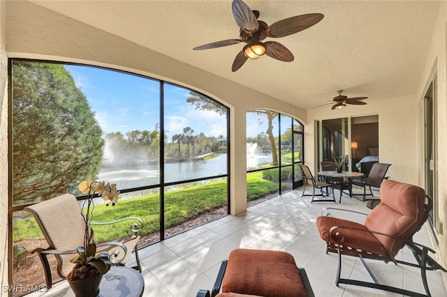 sunroom with a water view, a ceiling fan, and a healthy amount of sunlight