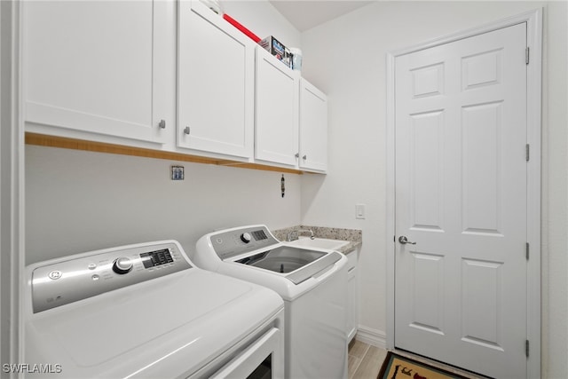 laundry room featuring sink, washer and clothes dryer, and cabinets