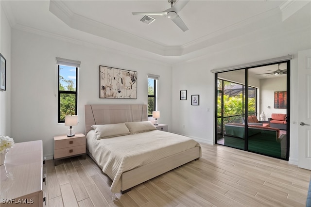 bedroom featuring ceiling fan, light hardwood / wood-style flooring, a tray ceiling, access to exterior, and crown molding