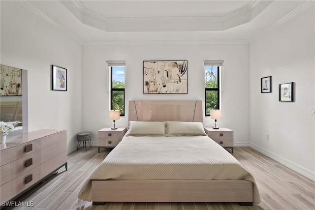 bedroom featuring a tray ceiling, light hardwood / wood-style flooring, and multiple windows