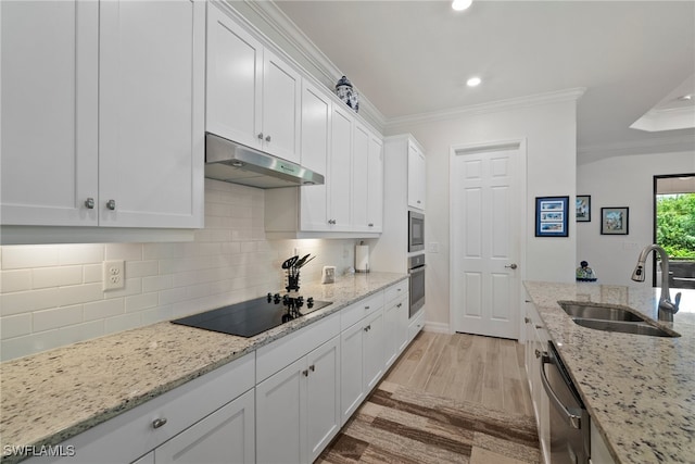 kitchen with light wood-type flooring, decorative backsplash, ornamental molding, appliances with stainless steel finishes, and sink