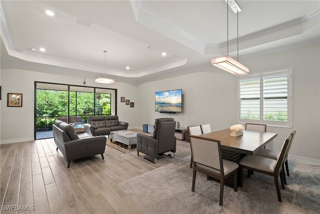 dining area with a tray ceiling, light hardwood / wood-style floors, and crown molding