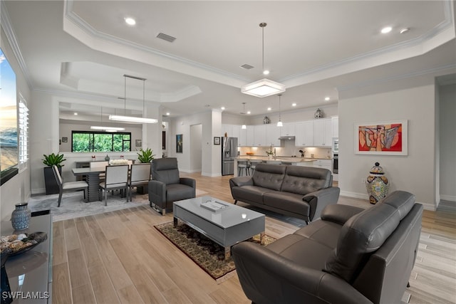 living room featuring light hardwood / wood-style flooring, crown molding, and a raised ceiling