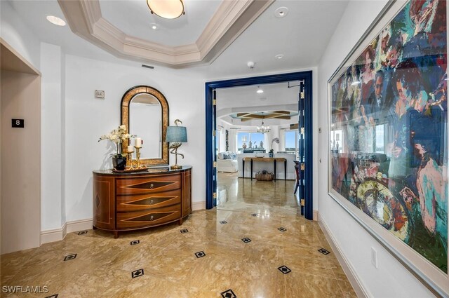 hallway with ornamental molding and a raised ceiling